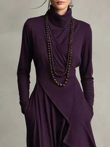 Detailansicht eines tiefvioletten Wickelkleids mit Rollkragen, langen Ärmeln und Taschen
