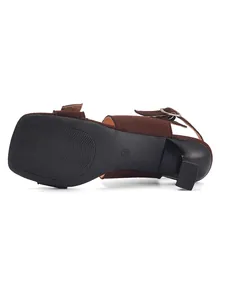 Bottom view of brown suede mule sandals showing sculptural heel and sole pattern