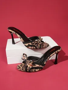 Detailed view of leopard print high heel sandals featuring an elegant bow decoration