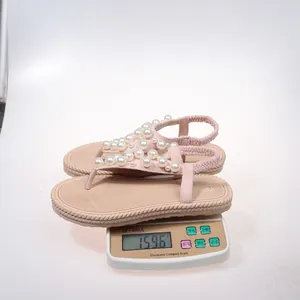 Misurazione del peso di sandali infradito rosa con perle su bilancia elettronica