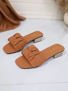 Detail van bruine sandalen met vierkante neus, gerimpelde band en glitterhak.
