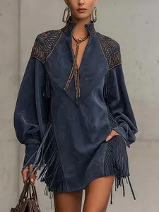 Détail d'une robe bleue à col en V avec des franges élégantes et broderies dorées