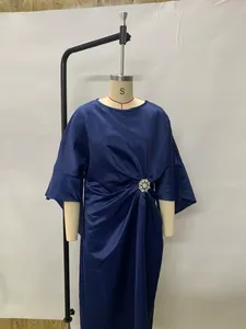 Elegant navy blue satin dress featuring a decorative flower brooch and draped waist.