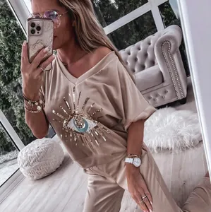 Close-up of stylish beige lounge set featuring a sequined evil eye graphic.
