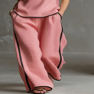 Dettaglio dei pantaloni rosa a gamba larga con finiture nere e design a contrasto