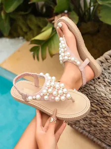 Dettaglio dei sandali infradito rosa con eleganti decorazioni in perle e suola spessa