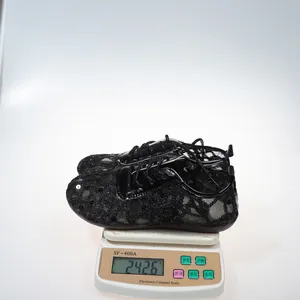 Close-up of black lace mesh flats on a digital scale showing product weight details.