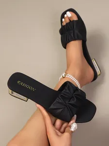 Detailweergave van de geplooide band en met strass versierde hak van zwarte modieuze sandalen