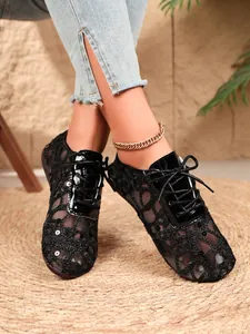 Detailed macro shot of women's black lace mesh flats with sequins and lace-up design