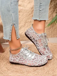 Close-up detail view of elegant silver lace mesh flat shoes with ribbon ties for women