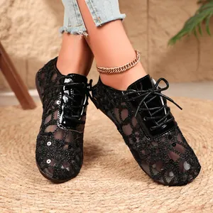 Close-up of elegant black lace mesh flat shoes with sequins and ties on a straw mat