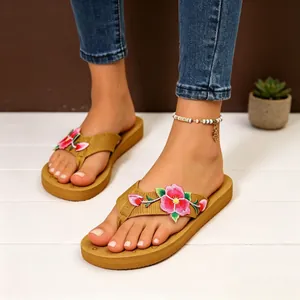 Infradito con zeppa da donna con ricami floreali rosa indossate per un look estivo casual.