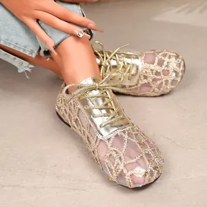 Close-up detail of women's golden lace mesh flat shoes with metallic laces and sequins.