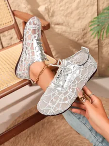 Close-up detail of silver lace mesh flats with sparkling sequins and lace-up design