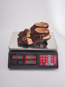 Close-up detail of brown suede square-toe sculptural heel sandals being weighed on a scale