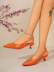 Détail élégant de sandales à talons bas orange à bout pointu portées par un mannequin