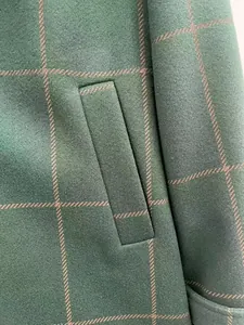 Detail shot of green plaid woolen fabric showing high-quality texture and pocket craft.