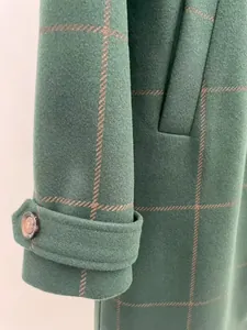 Detailed macro view of vintage green plaid wool coat sleeve cuff showing fabric texture