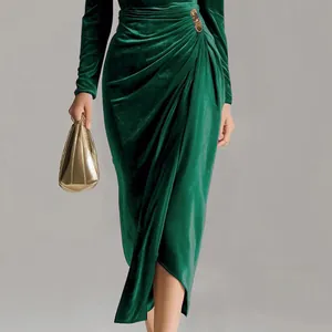 Close-up of elegant green velvet dress featuring pleated waist and decorative brooch