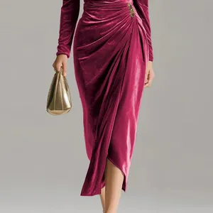 Detailed shot of an elegant magenta velvet ruched bodycon dress with long sleeves and slit.