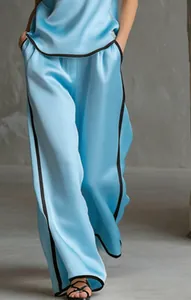 Dettaglio dei pantaloni larghi in raso celeste con eleganti profili neri a contrasto