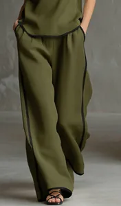 Dettaglio dei pantaloni larghi verde oliva con elegante profilo nero a contrasto.