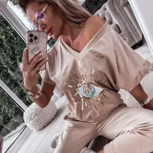 Trendy women's lounge set featuring a sequin Evil Eye motif on a beige short sleeve top
