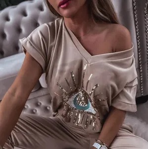 Detailed view of women's beige velvet set featuring a sparkling sequin Evil Eye pattern.