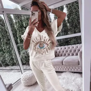 Detail of women's cream casual set with sequined evil eye motif on V-neck top