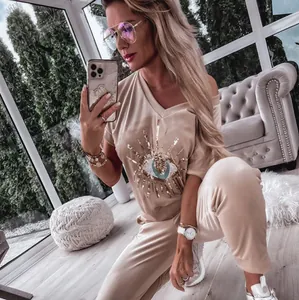 Full view of beige women's casual set featuring a detailed sequined evil eye graphic