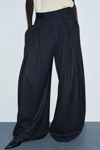 Detailed view of women's pinstripe wide-leg trousers with elegant deep pleats and high waist