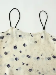 Primo piano di un top in raso a fiori con sottili spalline nere e tessuto leggero.
