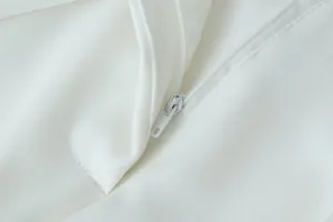 Macro detail shot showing the smooth white zipper closure on these elegant wide-leg trousers