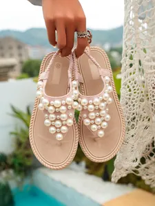 Dettaglio di sandali infradito rosa decorati con grandi ed eleganti perle bianche