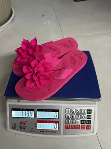 Infradito rosa leggere con grandi fiori in tessuto pesano 113,4 g su una bilancia
