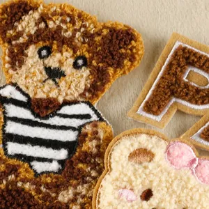 Gros plan sur des écussons ours en broderie bouclette et lettre P accessoire de couture
