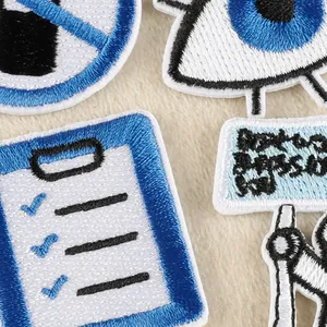 Blue and white embroidered iron-on patches with eye and clipboard designs for clothes