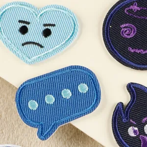 Detailed macro view of assorted blue cartoon embroidered patches for DIY clothing decoration.