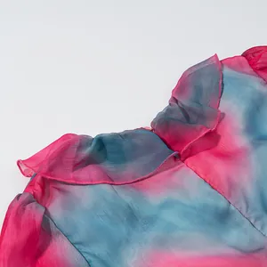 Gros plan détaillé sur le col à volants d'une robe en mousseline dégradée rose et bleu