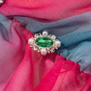 Gros plan détaillé d'une broche vintage à gemme verte avec perles et strass