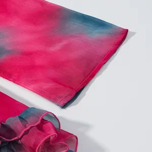 Gros plan détaillé d'une manche de robe en mousseline dégradé rose bleu avec volants