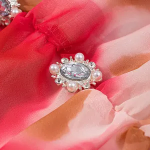 Gros plan sur une broche décorative en cristal et perles sur une robe à fleurs rose dégradé