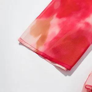 Gros plan détaillé de l'imprimé aquarelle rouge et rose sur la manche d'une robe en mousseline