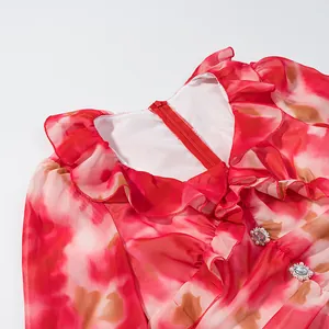 Gros plan d'une robe fleurie rouge avec col à volants et boutons décoratifs bijoux
