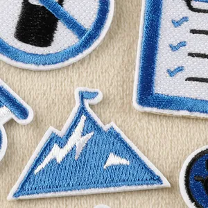 Detailed blue and white embroidered iron-on patches with mountain and icon designs