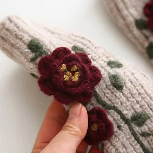 Close-up detail of handcrafted red crochet roses on a knit winter accessory sleeve