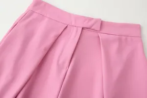 Close-up detail of pink wide-leg trousers showing waistband and front fly design