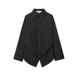 Dettaglio di una camicia nera a maniche lunghe con un esclusivo orlo drappeggiato asimmetrico.