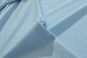 Λεπτομέρεια υφής γαλάζιου πλεκτού υφάσματος για γυναικείο εσωτερικό μπλουζάκι.