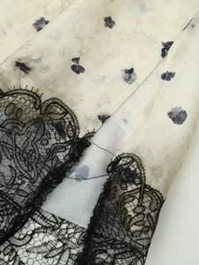Dettaglio ravvicinato di pizzo nero su tessuto di raso a fiori per top da donna elegante
